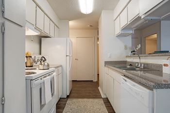 A kitchen with white appliances and a grey countertop